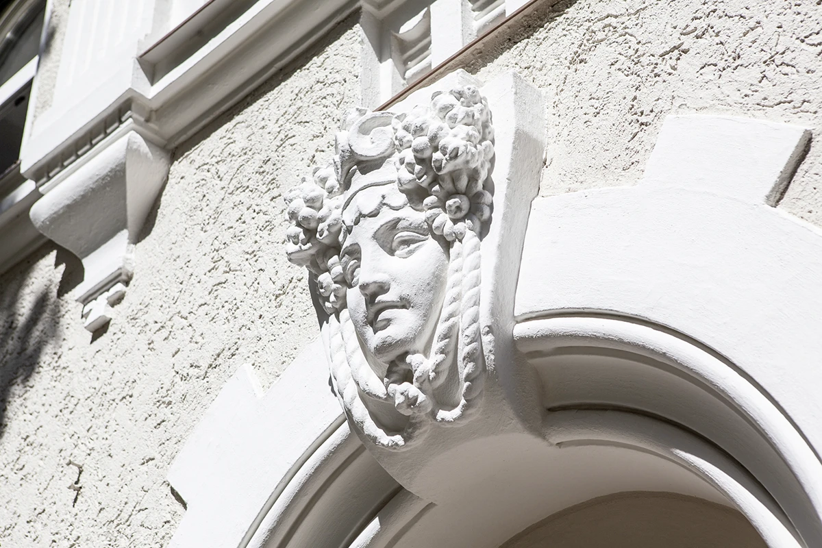 stoiber-architektur-muenchen-2026-sanierung-donnersbergerstr-05 Stuckmaske eines Frauenkopfs mit Frucht- und Blütenkranz als Schlussstein über einem Rundbogen