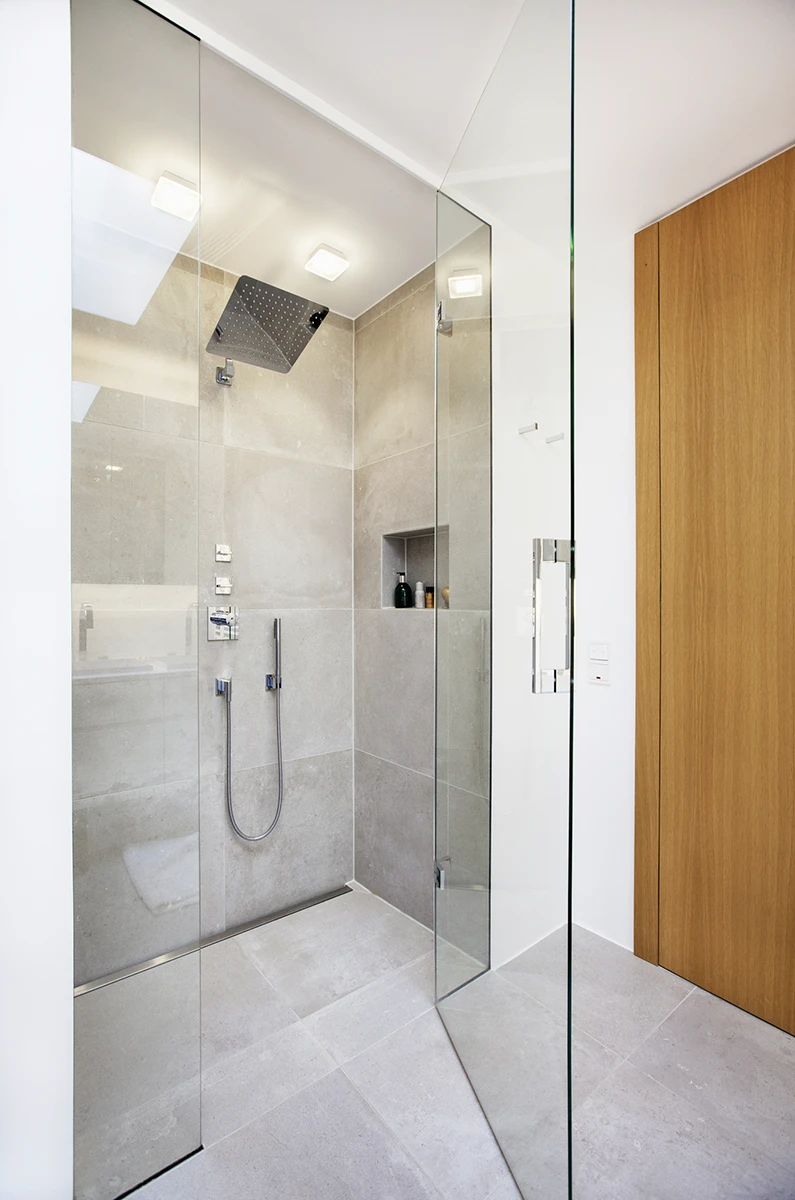 Badezimmer, grau gefliesst, bodengleiche Dusche mit Glastrennwand