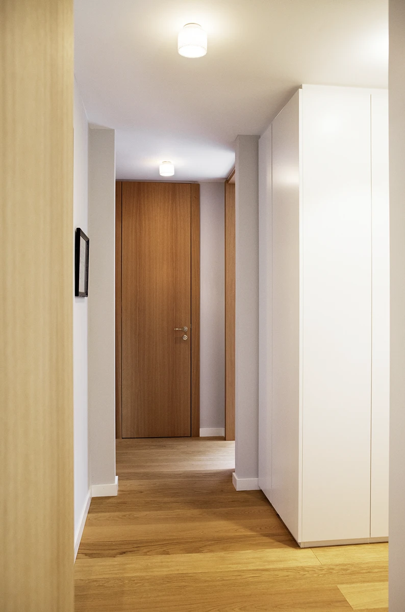 Blick durch den Flur auf die Eingangstür, seitlich Türen in die anderen Zimmer, Holboden, weisse Wände