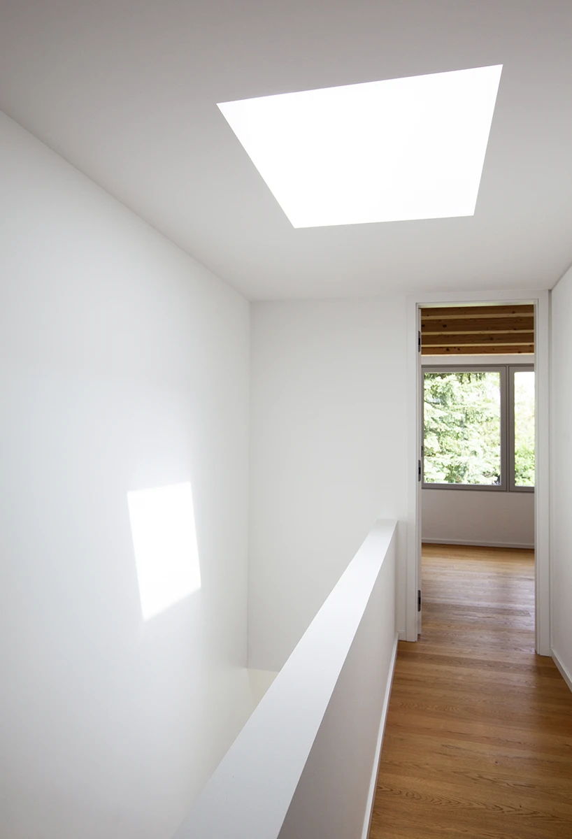 stoiber-architektur-neubau-einfamilienhaus_muenchen_flur_12 Lichtdurchfluteter Flur, dunkler Holzboden, links Treppenabgang, weisse Wände