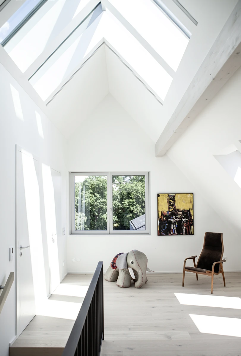 Wohnbereich Dachgeschoss mit nach oben offener Architektur, große helle Dachfenster, Holzboden, weisse Wände