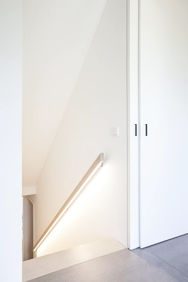 Geöffnete Schiebetür mit dahinter liegender Treppe nach unten, weisse Wände, Holzboden