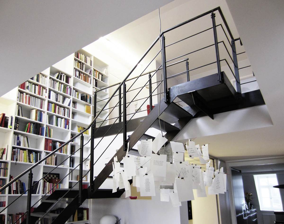 Treppe in das Dachgeschoss mit Bücherregal im Hintergrund, rechts offene Tür zur Küche