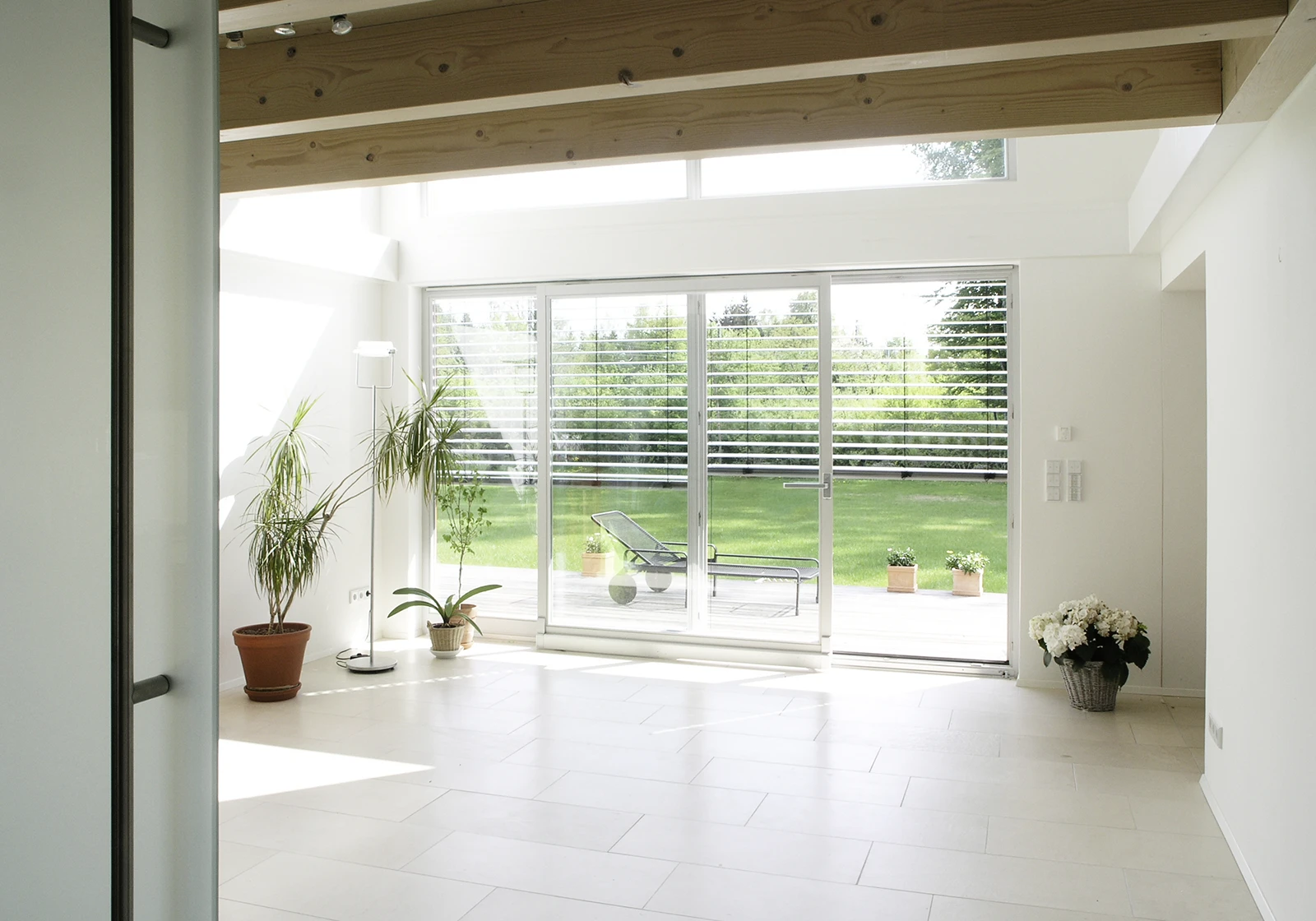 stoiber-architektur_dachgeschossausbau_neubau-anbau_holzbau_innen_wohnzimmer_06 Wohnzimmer mit gefliessten Boden, Blick durch große Fensterfront in den Garten, Anbau, Einfamilienhaus Umland München