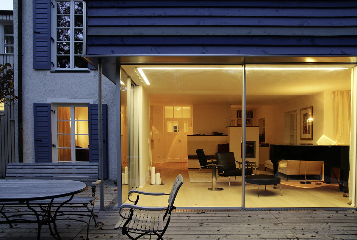 stoiber-architektur_sanierung-einfamilienhaus-anbau_muenchen-obermenzing_terasse-wohnen_02 Blick vom Garten auf den Anbau bei Abendstimmung