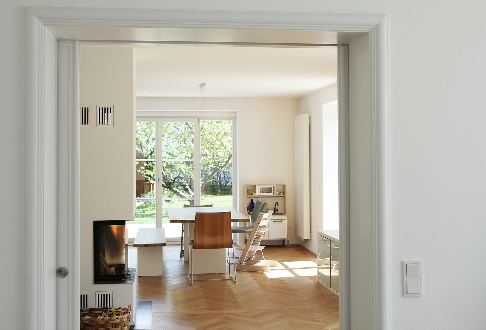 stoiber-architektur_sanierung_villa_sendling_essbereich_05 Blick aus dem Gang in den Wohn- Essbereich, links ein Kamin, Holzfussboden
