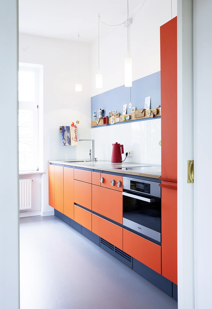 stoiber-architektur_umgestaltung-wohnkueche_muenchen_seitlich_04 Gesamtbild einer Küchenzeile, Fronten in rot/Orange, moderne Geräte, 2021