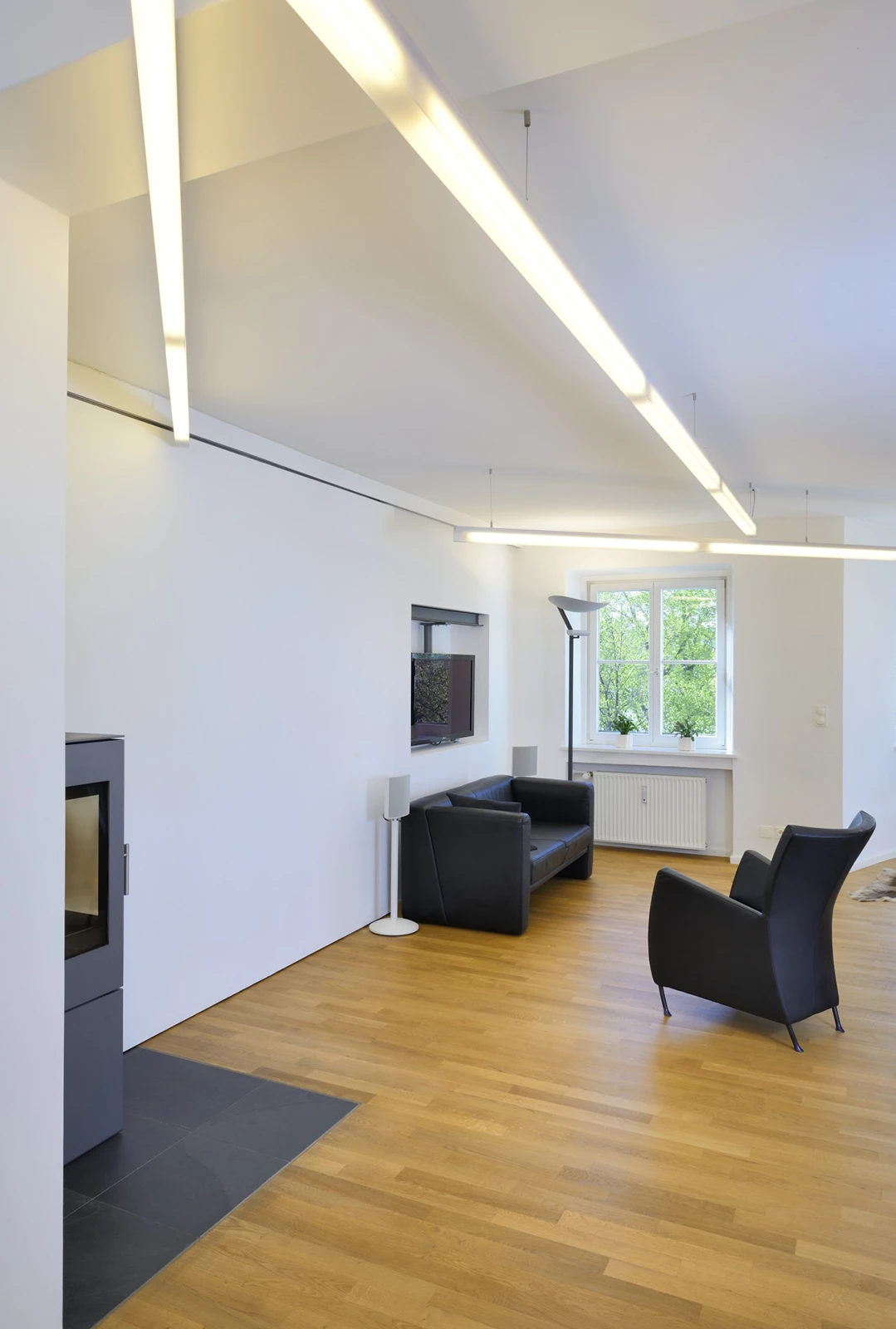 Wohnbereich der Wohnung mit Sofa, Sessel und Kamin, hohe Decke