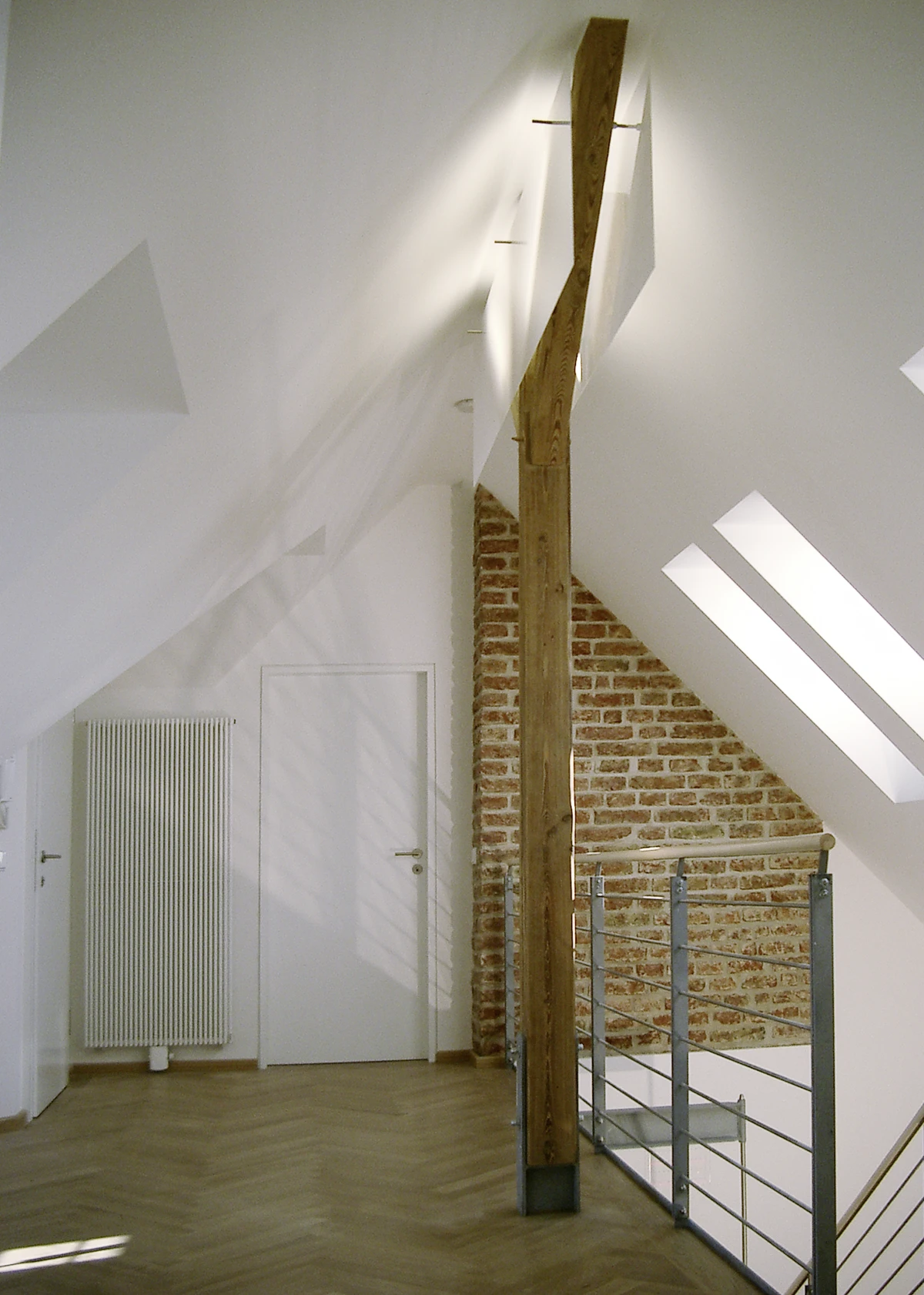 stoiber-architektur_denkmal_sanierung_dachgeschossausbau_muenchen_dach-innen_04 Helles Dachgeschoss mit Holzbalken, Sichtziegelwand, Dachfenstern, Stahlgeländer und Fischgrätparkett