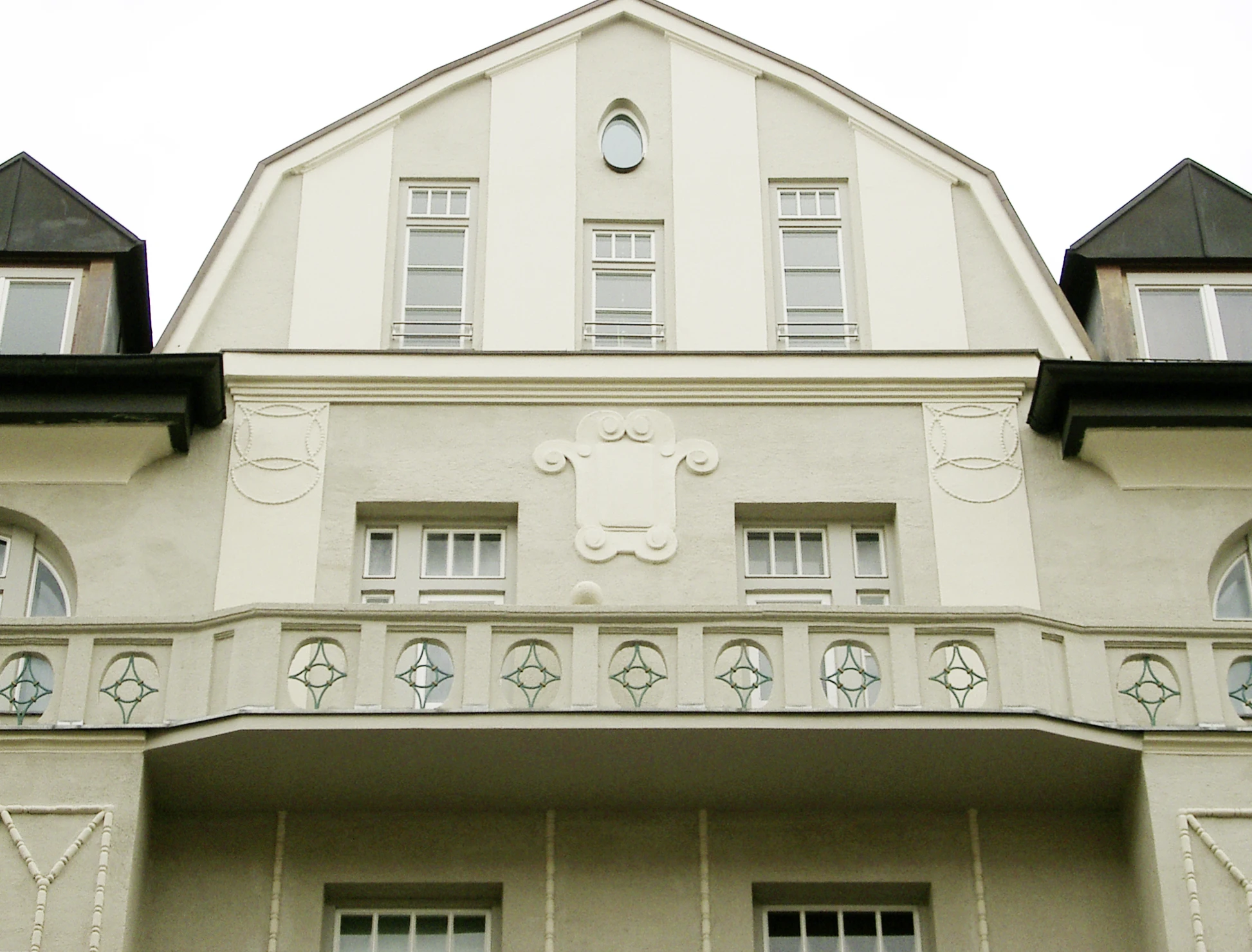 Jugendstilgiebel in Haidhausen mit ovalem Fenster, Stuckkartusche und Balkonbrüstung mit grünen Rautenornamenten