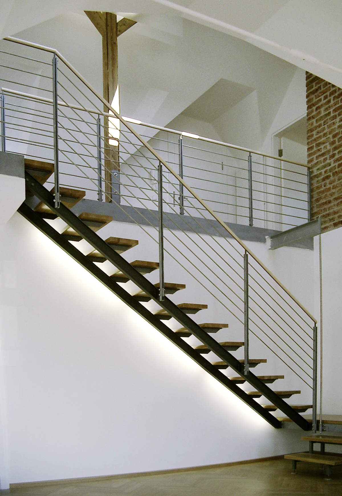 stoiber-architektur_denkmal_sanierung_dachgeschossausbau_muenchen_treppe-dachgeschoss_06 Stahltreppe mit Holzstufen und Stabgeländer, von unten beleuchtet, führt zur Galerie im Dachgeschoss